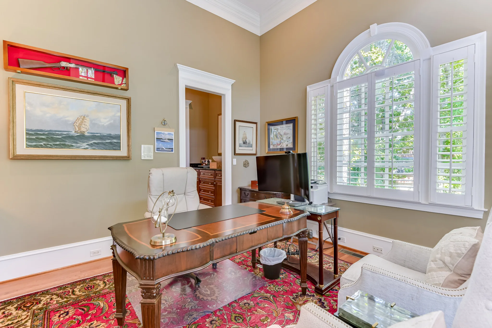 Dedicated office with a writing desk, seating, and a large arched window