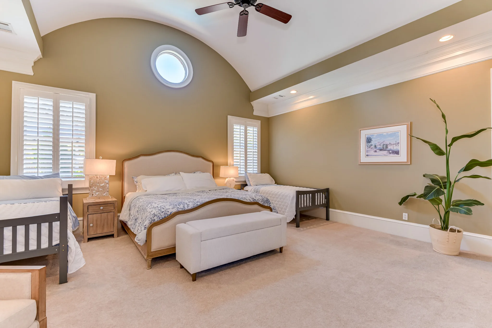 Upper-level primary bedroom with an arched ceiling and a circular accent window