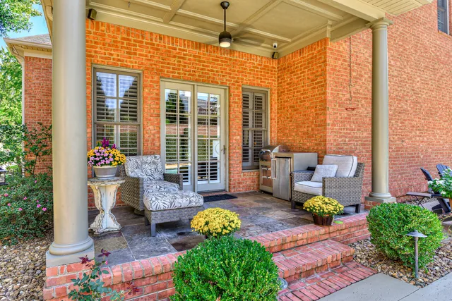 Covered back porch with upholstered lounge chairs and a grill